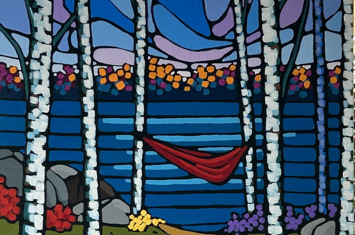 Red hammock between birch trees beside a blue lake